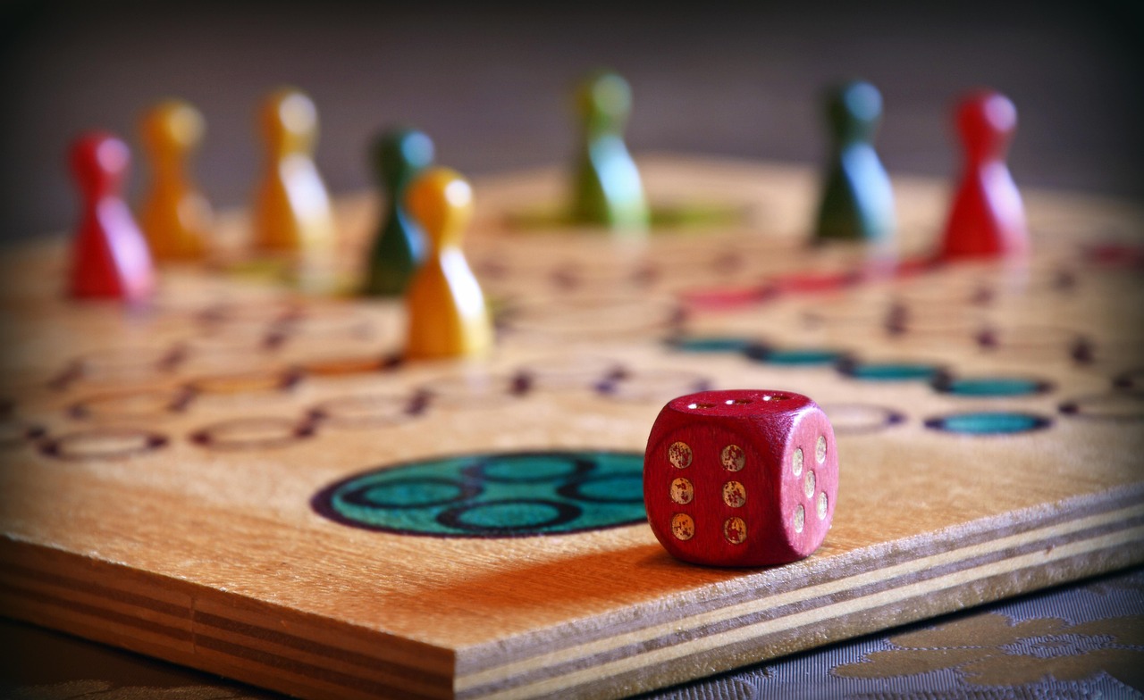 Plateau de jeu en bois avec des pions colorés et un dé rouge posé sur le plateau